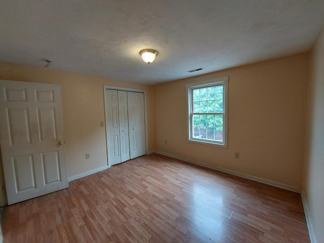 unfurnished bedroom featuring light wood-type flooring and a closet