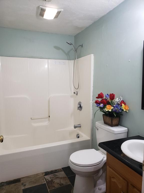 full bathroom with toilet, vanity, and shower / washtub combination