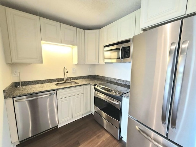 90 Quincy Shore Dr Unit 303, Quincy, MA 02171 - kitchen featuring appliances with stainless steel finishes, dark wood-type flooring, white cabinetry, and dark stone counters