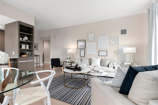 living room with wood finished floors, visible vents, and baseboards