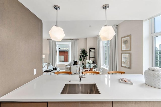 kitchen featuring decorative light fixtures, open floor plan, light countertops, and a sink