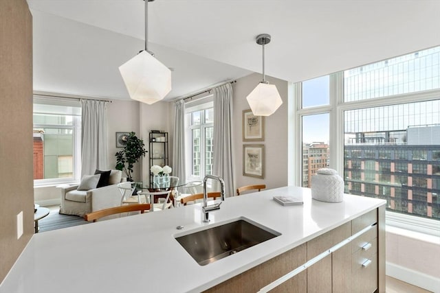 kitchen featuring a sink, pendant lighting, open floor plan, and light countertops