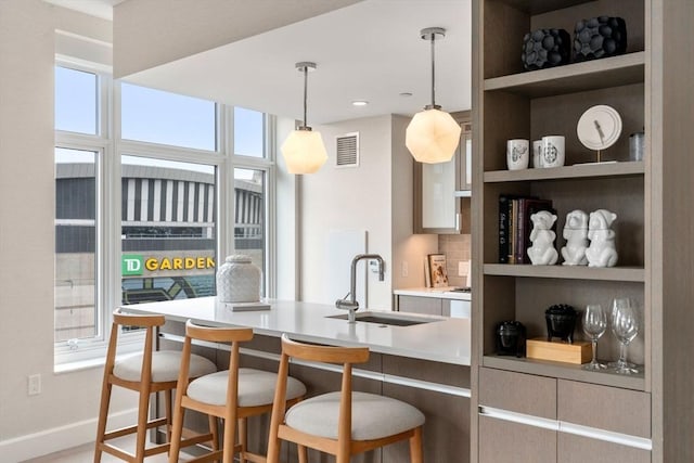 kitchen with a sink, open shelves, decorative light fixtures, a breakfast bar area, and light countertops