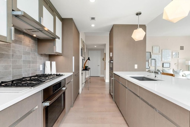 kitchen with visible vents, a sink, light countertops, appliances with stainless steel finishes, and wall chimney exhaust hood