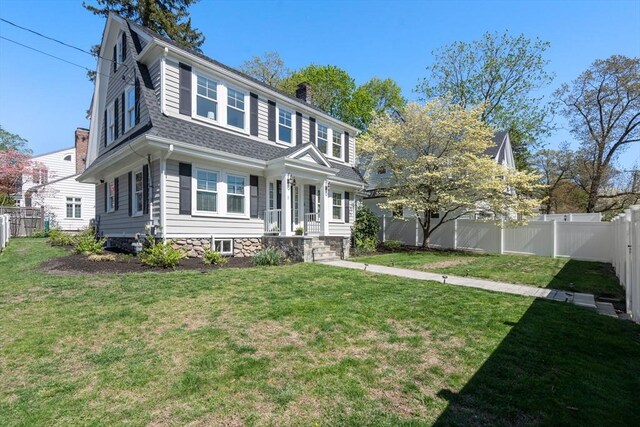 view of front of home featuring a fenced backyard, a front lawn, roof with shingles, and a chimney