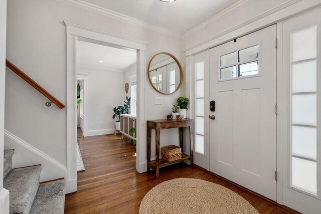 foyer entrance with baseboards, ornamental molding, stairs, and wood finished floors