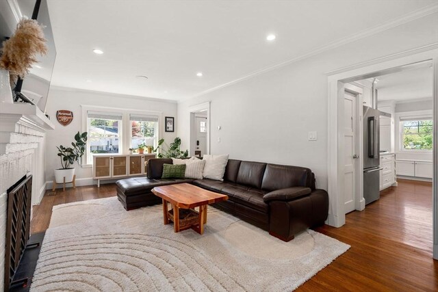 living room featuring recessed lighting, ornamental molding, dark wood-style flooring, and a brick fireplace