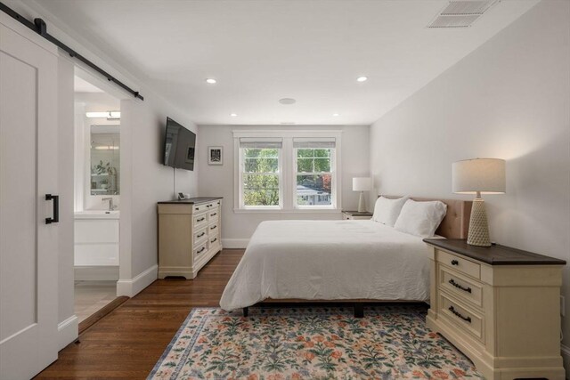 bedroom featuring recessed lighting, dark wood finished floors, a barn door, and visible vents