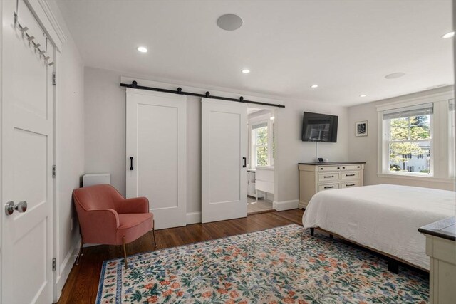 bedroom with recessed lighting, baseboards, a barn door, and wood finished floors