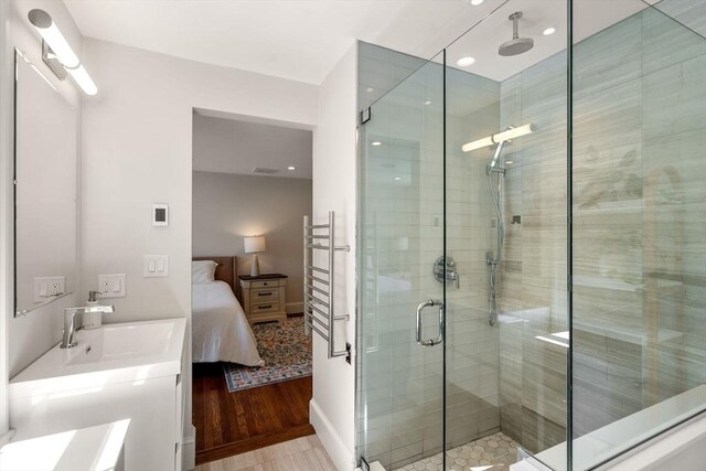 bathroom with a shower stall, wood finished floors, vanity, baseboards, and ensuite bath