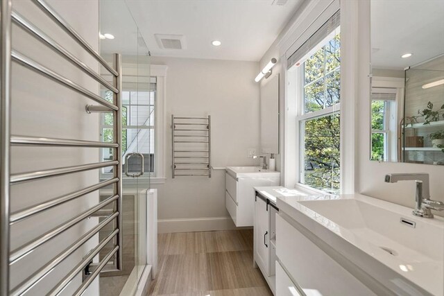 full bathroom with two vanities, baseboards, a shower stall, and a sink