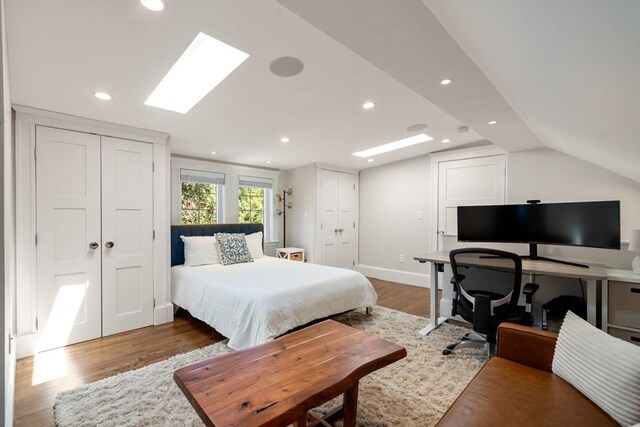 bedroom featuring recessed lighting, baseboards, multiple closets, and wood finished floors