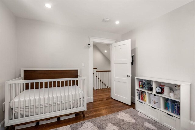 bedroom with recessed lighting, wood finished floors, and a nursery area