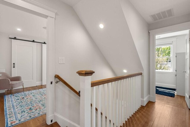 staircase featuring visible vents, a barn door, and wood finished floors