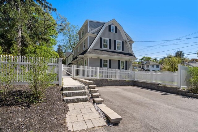 view of front of home featuring a shingled roof, fence private yard, and a gambrel roof
