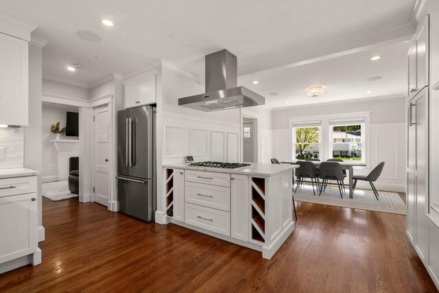 kitchen featuring island range hood, high quality fridge, light countertops, a decorative wall, and white cabinetry