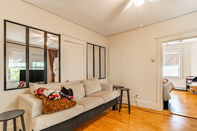 living room featuring ceiling fan, baseboard heating, and light wood-type flooring