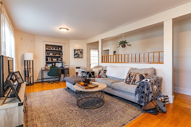 living room featuring hardwood / wood-style floors, a baseboard heating unit, and built in shelves