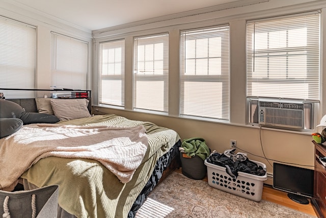 bedroom with light hardwood / wood-style floors, multiple windows, cooling unit, and crown molding