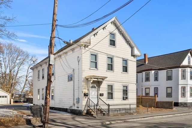 italianate house with entry steps, fence, and a chimney