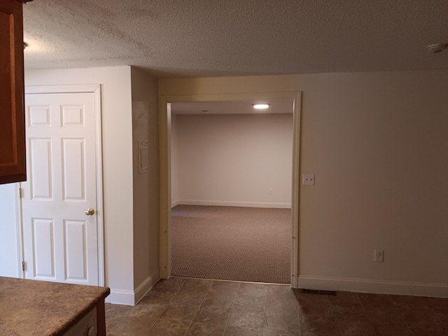 hallway with a textured ceiling and dark tile floors