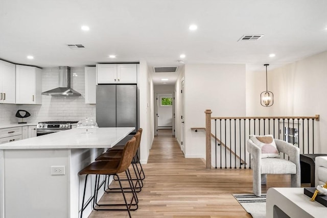 26 Parsons Dr, Swampscott, MA 01907 - kitchen featuring wall chimney exhaust hood, stainless steel appliances, light wood-type flooring, recessed lighting, and a breakfast bar area