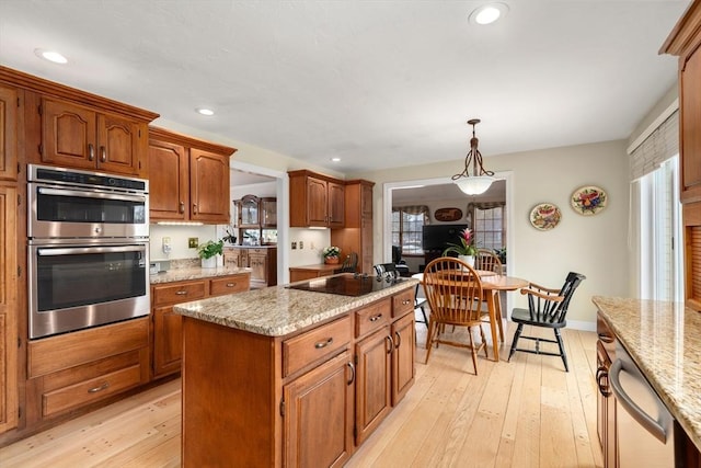 kitchen featuring light wood-style flooring, appliances with stainless steel finishes, brown cabinets, and a center island