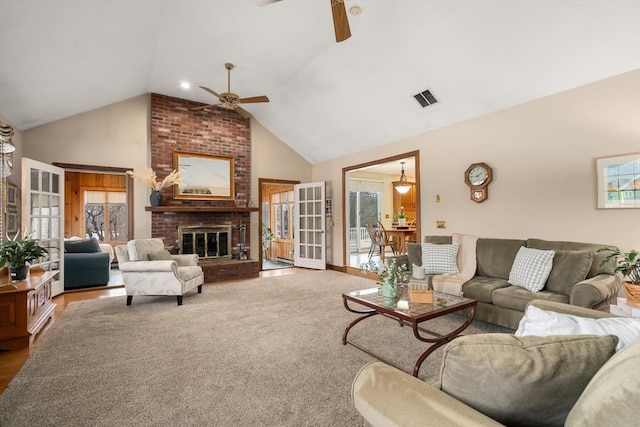 living area with high vaulted ceiling, a fireplace, visible vents, and a ceiling fan