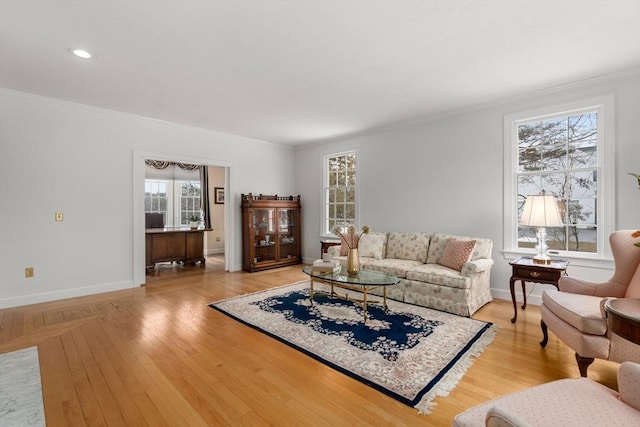 living room featuring light wood-type flooring, baseboards, and ornamental molding