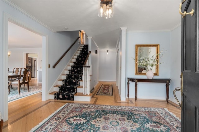 entrance foyer with ornamental molding, stairway, baseboards, and wood finished floors