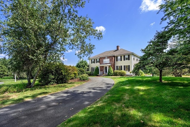 view of front of house with a front lawn, a chimney, and brick siding