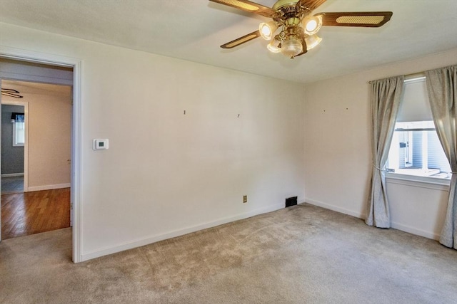 carpeted spare room with a ceiling fan and baseboards