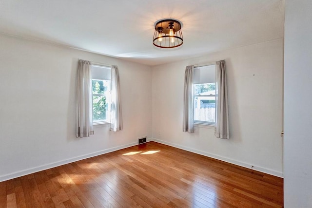 unfurnished room with plenty of natural light, wood-type flooring, and baseboards