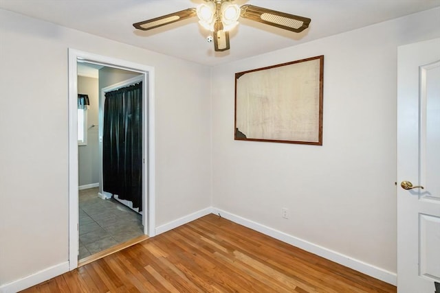 unfurnished room featuring ceiling fan, light wood-style flooring, and baseboards