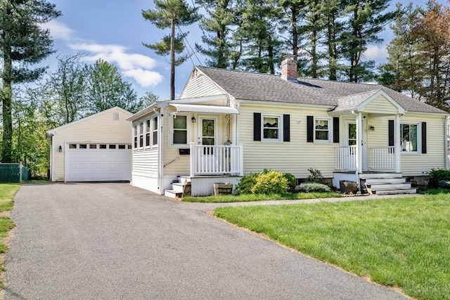 view of front of house with a chimney, an outbuilding, a front yard, a shingled roof, and a detached garage