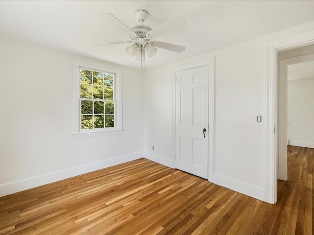 unfurnished bedroom with wood finished floors, a closet, a ceiling fan, and baseboards