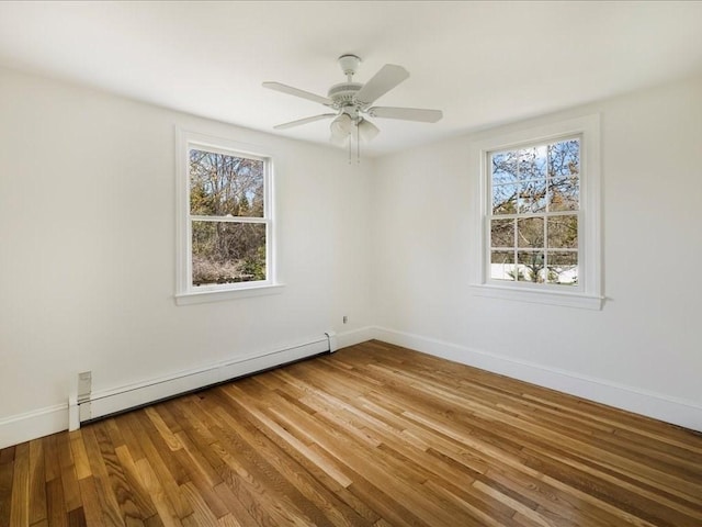 spare room with baseboards, a wealth of natural light, wood finished floors, and a baseboard radiator