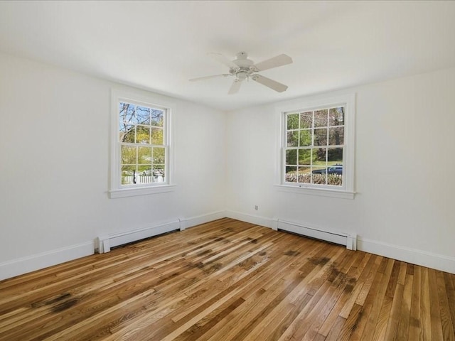 spare room featuring a healthy amount of sunlight, wood finished floors, and a baseboard radiator