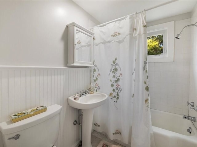 bathroom featuring toilet, shower / bath combo, and wainscoting