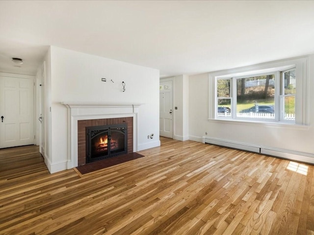 unfurnished living room with baseboards, wood finished floors, a baseboard heating unit, and a fireplace