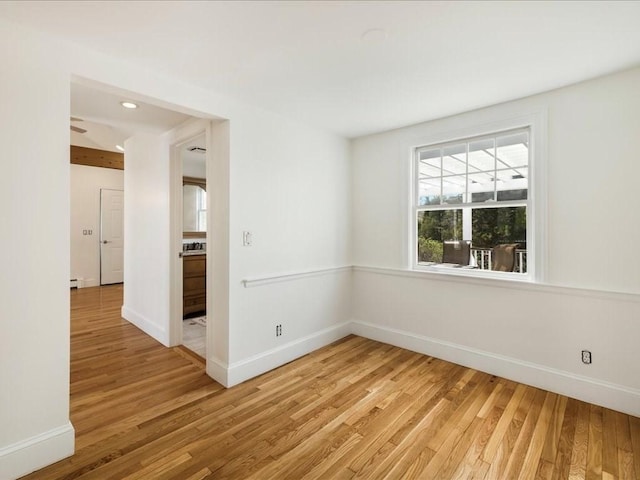 spare room featuring light wood-style floors, recessed lighting, and baseboards