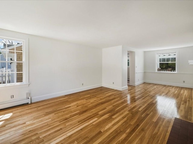 spare room featuring wood finished floors, plenty of natural light, and baseboards