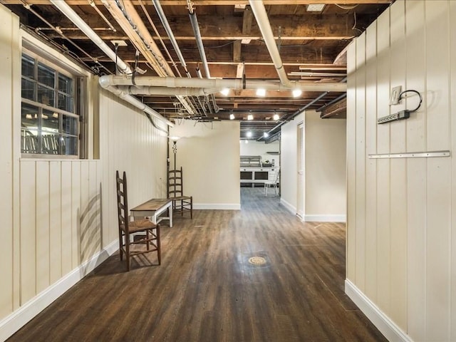 finished basement featuring baseboards, wood finished floors, and wooden walls