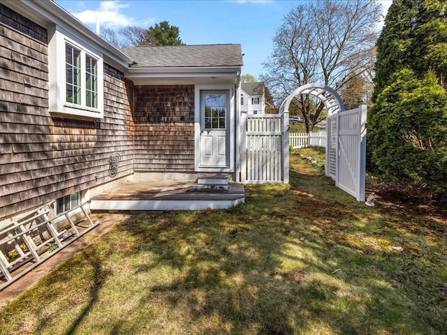 doorway to property featuring a lawn and fence