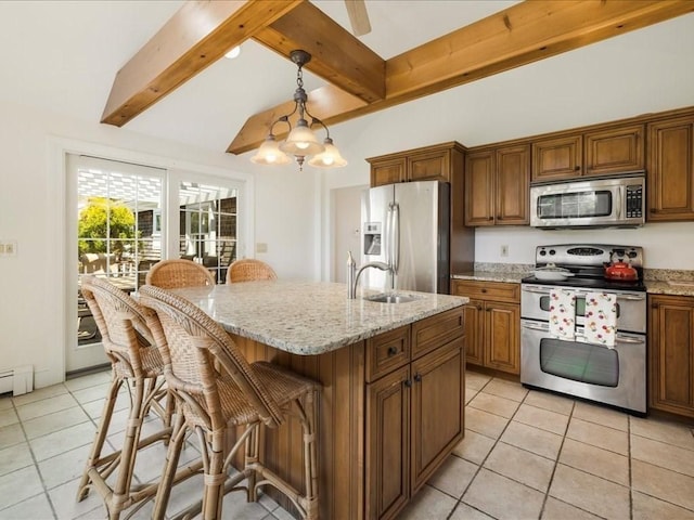 kitchen featuring a sink, stainless steel appliances, light tile patterned floors, brown cabinetry, and a breakfast bar