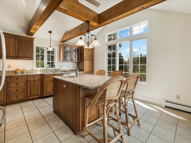 kitchen with beam ceiling, brown cabinetry, light tile patterned floors, and light stone counters