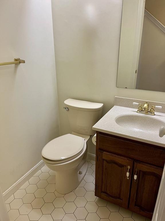 bathroom featuring toilet, baseboards, and vanity