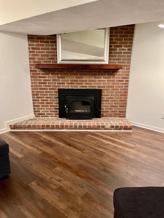 room details with a brick fireplace, a textured ceiling, baseboards, and wood finished floors