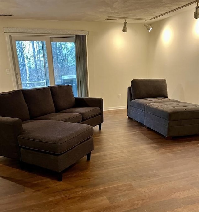 living room with rail lighting, visible vents, baseboards, and wood finished floors