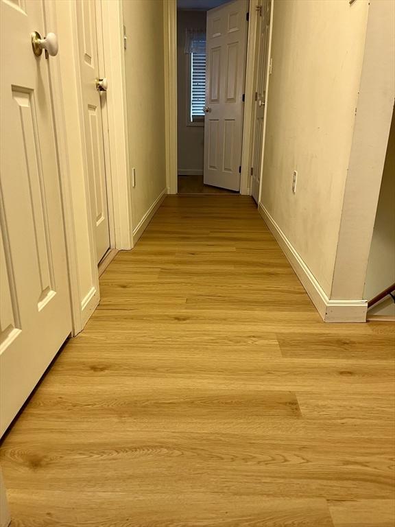 hall with light wood-style floors and baseboards